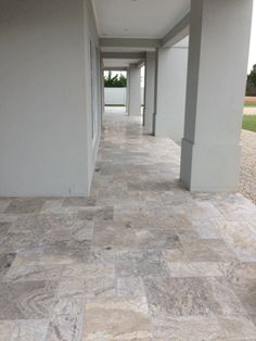 an empty hallway with white walls and tile flooring on both sides, leading into the distance