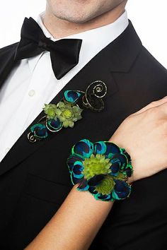 a man in a tuxedo and bow tie with two flower brooches on his lapel