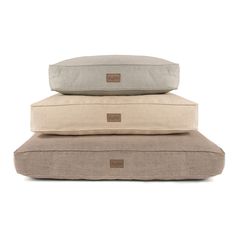 three pillows stacked on top of each other, one in beige and the other in grey