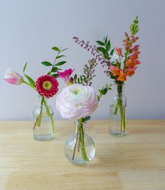 three vases with flowers in them on a table