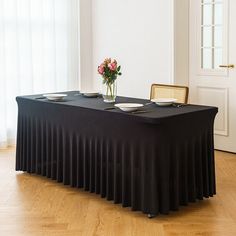 a black table with plates and flowers on it in front of a white door,