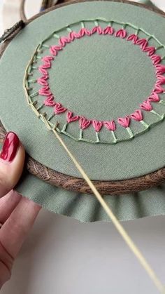 someone is stitching something on a piece of fabric with a needle in the shape of a circle