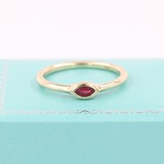 a gold ring with a red stone in it sitting on top of a blue box