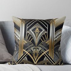 a black and gold art deco design throw pillow on a couch with pillows in the background