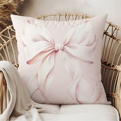 a white pillow with a pink bow on it sitting next to a wicker chair