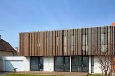 a house with wooden slats on the front and side of it, next to a brick building