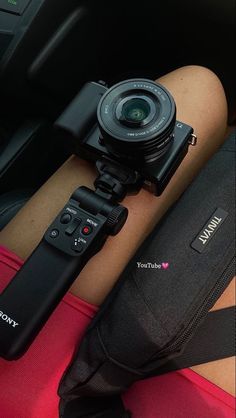 a camera sitting on top of a person's arm next to a red bag