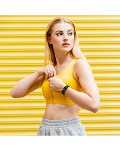 a woman in a yellow top is holding her hand on her hip and looking at the camera