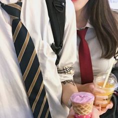 a man and woman are eating ice cream cones with strawberries in their hands while wearing neck ties