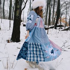 a woman walking through the snow in a dress and hat