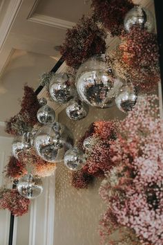 several disco balls hanging from the ceiling in front of a wall with flowers on it