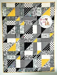 a black and yellow patchwork quilt hanging on a wall with a dog sticker