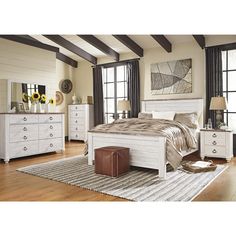 a white bed sitting on top of a wooden floor next to a dresser and mirror