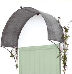 an arch over a green door with flowers growing on the top and bottom part of it