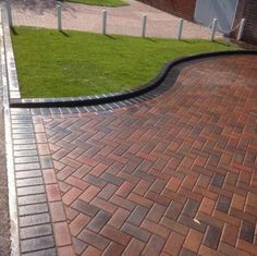 a brick walkway with grass in the background