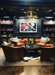 a living room with two chairs and a table in front of a bookshelf