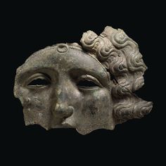 an ancient mask with curly hair and eyes