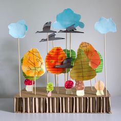 a group of paper trees on top of a wooden table with birds flying over them