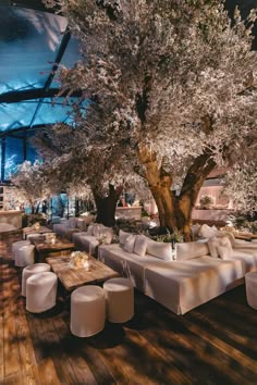 an outdoor dining area with tables and white linen covered benches under a cherry blossoming tree