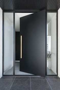 an open door leading into a room with white walls and black flooring on the outside