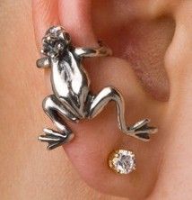 a close up of a person wearing an earring with a frog on it's side