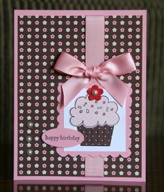 a card with a cupcake on it and a pink ribbon tied around the edge