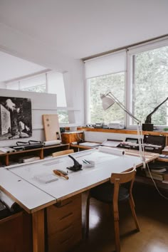 an art studio with lots of desks and artwork on the walls, along with large windows