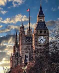 the big ben clock tower towering over the city of london, england with clouds in the background