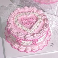 a pink heart shaped cake sitting on top of a white countertop next to a box