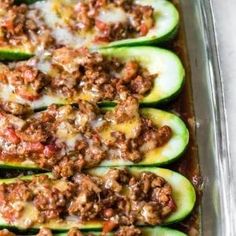 stuffed zucchini boats with meat and sauce in a baking dish on a table