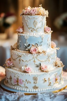 a three tiered wedding cake with pink flowers on the top and gold trimmings