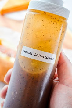 a hand holding a bottle with an onion sauce in it that says sweet onion sauce