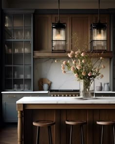 a kitchen with wooden cabinets and marble counter tops, flowers in a vase on the island