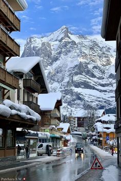 the mountains are covered in snow as people walk down the street