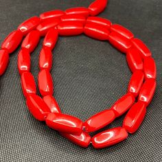 a red necklace is sitting on a gray surface and looks like it has been made out of plastic beads