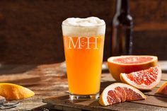 a glass filled with beer next to sliced grapefruits