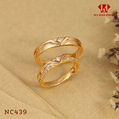 two gold wedding rings with diamonds on top of each other next to some dried flowers