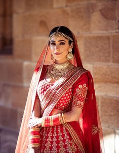 a woman wearing a red and gold bridal outfit