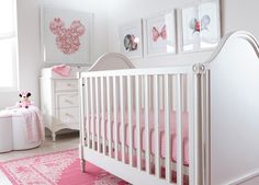 a white crib with pink bedding and pictures on the wall in a bedroom