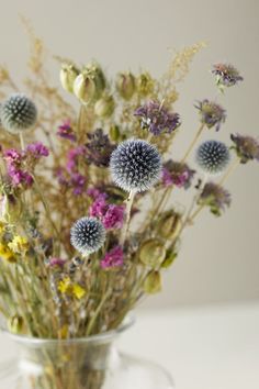 a glass vase filled with lots of wildflowers on top of a white table