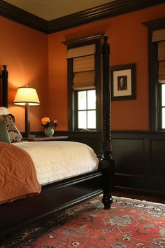 a bedroom with an orange wall and white bedspread on the bed is lit by two lamps