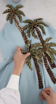 someone is making a palm tree decoration out of sequins on a blue dress