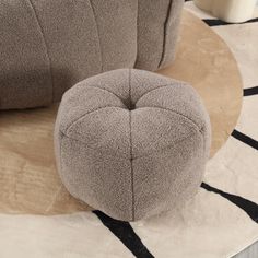 a round ottoman sitting on top of a rug next to a white and black chair