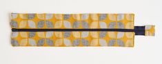 a yellow and grey pencil case on a white background with a black zippered closure