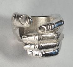 **Please note that we dispatch on Tuesdays unless special delivery express option is paid for** Sterling silver 'hand ring'. Original design carved in wax then lost wax cast into sterling silver.  Very large piece which weighs approximately 42g in silver.  Shown in a size S, and adjustable to ring sizes P-V.  A significant size adjustment may alter the appearance. PLEASE NOTE THE PHOTO ON THE WOMAN IN THE REVIEW IS A SIZE J AND TO MAKE IT LOOK LIKE THAT AT A LARGER SIZE WILL REQUIRE A £40 SUPPLEMENT. Please contact us to discuss.  First class recorded post included, with a supplement for special delivery. Wax Cast Rings, Wax Jewelry, Lost Wax Ring, Hand Shaped Ring, Lost Wax Casting Rings, Wax Carved Ring, Lost Wax Jewelry, Space Rings, Hand Ring