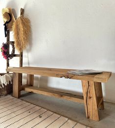 a wooden bench sitting on top of a rug next to a hat rack and vase