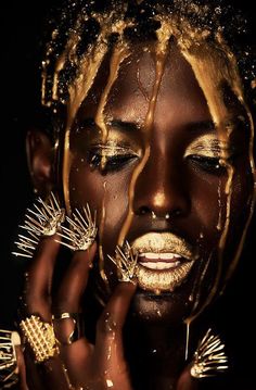 a woman with gold makeup and nails on her face