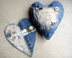 two denim heart shaped ornaments with buttons and thread on the sides, one has a message written on it