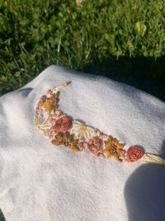 a piece of cloth with flowers on it laying in the grass next to a person's hand