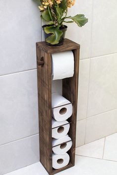 a toilet paper holder with two rolls of toilet paper and a potted plant in it